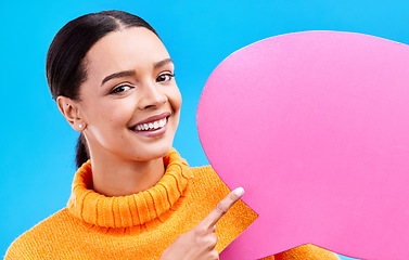 Image showing Speech bubble, smile and portrait of woman pointing to banner in studio for advertising on blue background. Face, happy and girl with poster, mockup and space for social media, announcement or news