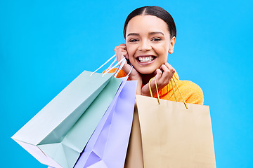 Image showing Shopping bags, excited and woman portrait with a smile and happiness from boutique sale. Happy, customer and female model with store bag and sales choice in isolated blue background and studio