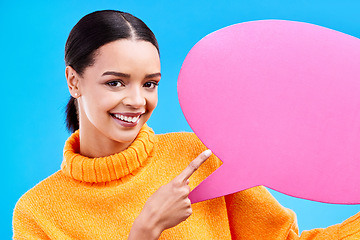 Image showing Speech bubble, happy and portrait of woman pointing to banner in studio for advertising on blue background. Face, smile and girl with poster, mockup and space for social media, announcement or news