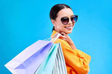 Image showing Shopping bags, studio and woman portrait with deal and happiness from boutique sale. Happy, customer and wealthy female model with store bag and sales choice in isolated blue background with person