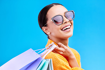 Image showing Shopping bags, retail and woman portrait with a smile and sunglasses from boutique sale. Happy, customer and female model with store bag and sales choice in isolated blue background in studio