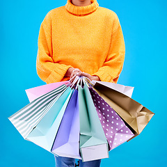 Image showing Woman, hands and shopping bags for purchase, sale or luxury accessories against a blue studio background. Hand of female shopper holding gift bag, buy or discount presents of retail products or items