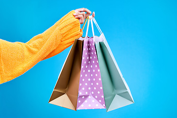 Image showing Woman, hands and shopping bags in studio of purchase, luxury accessories or sale against a blue background. Hand of female shopper holding gift bag, buy or presents of retail products on mockup