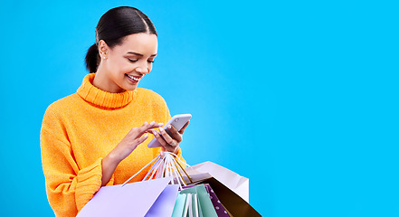 Image showing Happy woman, phone and shopping bags on mockup for purchase, sale or discount against a blue studio background. Excited female shopper smiling on mobile smartphone holding gift bag on copy space