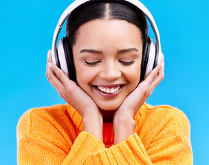 Image showing Headphones, happy music and woman in studio, blue background and backdrop. Smile, female model and listening to radio, streaming album and excited audio connection, sound and subscription to podcast