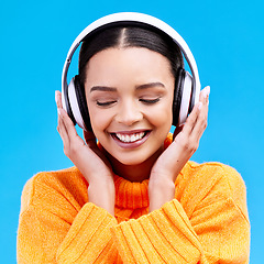 Image showing Headphones, happy woman and listening to music on blue background, studio and color backdrop. Gen z female model streaming audio, album and media connection to radio, sound and subscription podcast