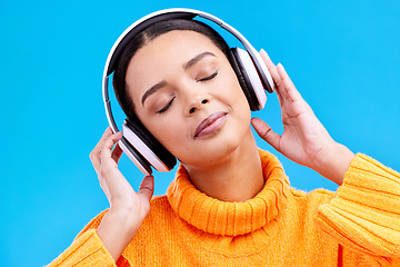 Image showing Headphones, calm music and woman in studio, blue background and backdrop. Peace, female model and listening to music, relax and streaming album on audio connection, sound or hearing zen radio podcast