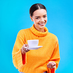 Image showing Woman, portrait and smile with coffee in studio for happiness for cafe advertising and mockup. Face of a happy female model giving tea cup on a blue background in hand for motivation and hospitality