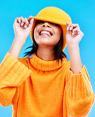 Image showing Fashion, happy and cover with woman and beanie in studio for hiding, winter and goofy. Playful, happiness and smile with female and knitted hat isolated on blue background for funny, silly and cool