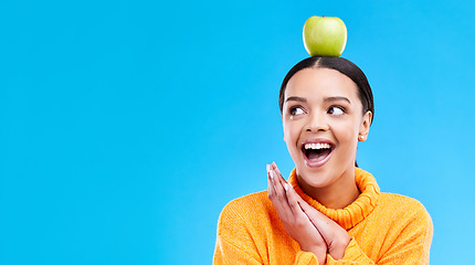 Image showing Wow, apple on head and a woman in studio on a blue background for product placement on mockup. Surprise, balance and space with an attractive young female posing to promote health, diet or nutrition