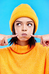 Image showing Silly, goofy and young woman in a studio with a comic, funny and crazy face expression. Funny, humor and beautiful female model from Puerto Rico touching her cheeks isolated by a blue background.