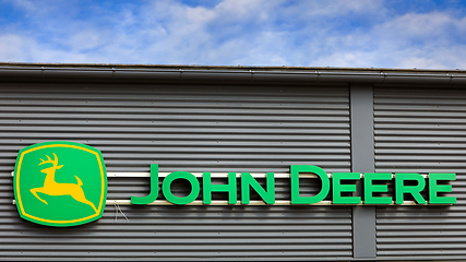 Image showing John Deere Logo With Blue Sky White Clouds 