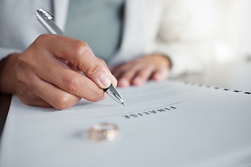 Image showing Signature, ring and divorce paper of a woman at table with legal paperwork, anxiety or documents. Female person sign with pen on papers with wedding band jewellery for separation, cheating or mistake