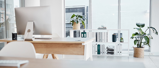 Image showing Empty office, interior and computer on desk in workplace, company or workspace. Room, desktop and table with corporate furniture, plants and window with modern design for business with nobody.