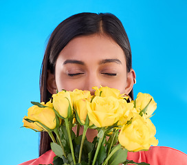 Image showing Smell, flower bouquet and roses with woman in studio for gift, satisfaction and spring. Relax, happy and floral present with female isolated on blue background for aroma, natural and products