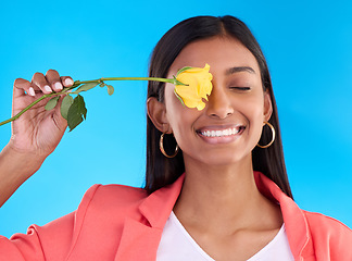 Image showing Happy, smile and woman with a flower in studio for a floral gift for valentines day or anniversary. Happiness, excited and Indian female model with yellow rose as present isolated by blue background.