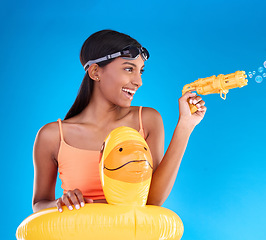 Image showing Bubbles, summer swimsuit and woman with bubble gun in a studio with fun and happiness. Isolated, blue background and happy female model with playful smile and swimming outfit for pool entertainment