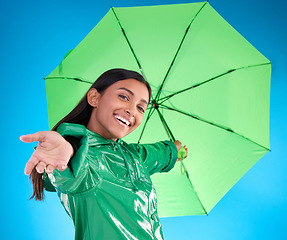 Image showing Portrait, smile and woman with umbrella, excited and expression against blue studio background. Face, female and person with cover from rain, happiness and excitement with joy, adventure or insurance