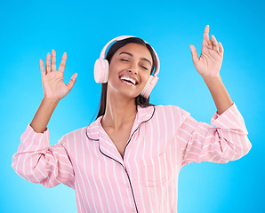 Image showing Smile, dance and woman in pajamas, headphones and inspiration against a blue studio background. Female, happy and lady with headset, waking up and dancing for motivation, wellness and streaming music