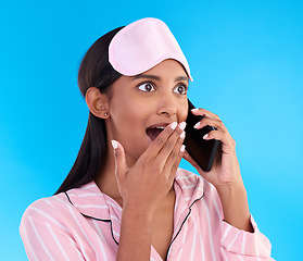 Image showing Phone call, surprise and female in pyjamas in studio with shocking, winning or good news. Communication, shock and woman model having gossip conversation with wtf, omg or wow face by blue background.