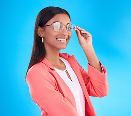 Image showing Woman, glasses and happy portrait in studio with a smile for eye care and vision with frame or lens. Smile of Indian female model person on a blue background with specs for fashion and business