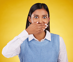 Image showing Portrait, wow and gossip with a woman on a yellow background in studio looking surprised by an announcement. Face, shock and news with an attractive young female standing hand over mouth in awe