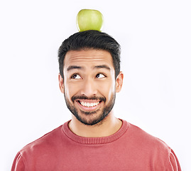 Image showing Happy, apple and balance on a head with a man in studio isolated on a white background for diet or nutrition. Smile, nutritionist and food with a healthy young male balancing fruit for detox or fiber