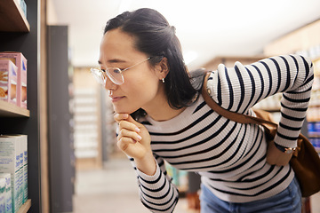 Image showing Thinking, woman and choice of shopping at shelf, retail products and reading grocery label of brand information. Female customer, decision and supermarket store for groceries, sales or consumer price