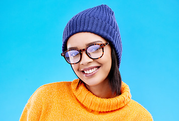 Image showing Portrait of woman in winter fashion with smile, beanie and glasses isolated on blue background. Style, happiness and gen z girl in studio backdrop with happy face and warm clothing for cold weather.