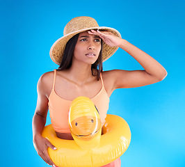 Image showing Studio, shocked woman on beach and vacation on blue background, looking or search with hat and hand on face. Travel, pool holiday and worried girl with inflatable rubber duck, ocean wear on holiday.