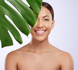 Image showing Portrait, leaf and woman in studio for skincare, dermatology and cosmetic on purple background. Beauty, face and girl model relax, smile and happy with glowing skin, cosmetology or monstera treatment