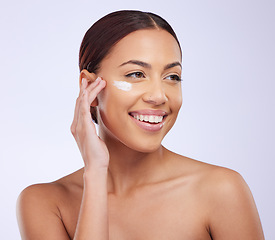 Image showing Woman, skincare cream and smile in studio for self care, thinking or beauty with product application on face. Girl, model and facial skin wellness with cosmetics, health and dermatology by background