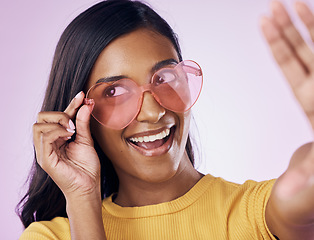 Image showing Heart, glasses and selfie by indian woman in studio happy, cheerful and fun on purple background. Sunglasses, pose and female gen z fashion influencer smile for profile picture, photo or blog post