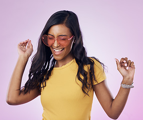 Image showing Dancing, sunglasses and cool woman excited, happy and confident isolated in a pink studio background with joy. Singing, music and young genz female dance in celebration of a party energy with glasses