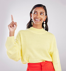 Image showing Woman is pointing up, smile and marketing with announcement and product placement on studio background. Advertising, logo promo and branding with happy Indian female, show with direction and choice