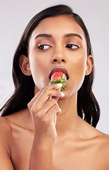 Image showing Eating strawberry, studio or healthy Indian woman with skincare beauty or wellness in headshot. Food nutrition, bite or face of girl model with vitamin c or red fruits isolated on a white background