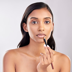 Image showing Woman with lip pencil, face and portrait with makeup, beauty and cosmetic product on studio background. Indian female, cosmetics liner for lips and lipstick with healthy skin and cosmetology