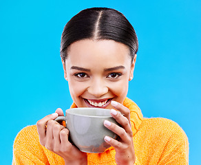 Image showing Coffee, woman portrait and smile in studio with happiness and mug. Isolated, blue background and happy female model or young person with casual winter fashion, latte or tea drink with smiling joy