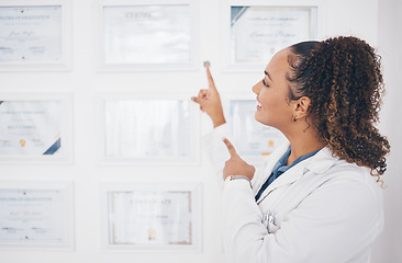 Image showing Graduation, pointing and healthcare award with a woman proud of her medical achievement in the hospital. Face, smile and happy with a female medicine professional showing her certificate in a clinic