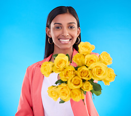 Image showing Happy, gift and a portrait of a woman with flowers isolated on a blue background in a studio. Smile, holding and a girl giving a floral bouquet as a present, showing a flower and fresh roses