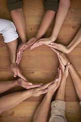 Image showing Hands, teamwork and circle with business people on a wooden table in the office closeup from above. Collaboration, synergy and an employee group or team together in a huddle during a meeting at work