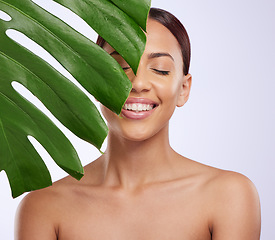 Image showing Smile, leaf and woman in studio for skincare, dermatology and cosmetic on purple background. Beauty, face and girl model relax, calm and happy with glowing skin, cosmetology or monstera treatment