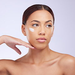 Image showing Woman, skincare cream and thinking in studio for self care, aesthetic or beauty with product application on face. Girl, model and facial skin wellness with cosmetic, health or dermatology by backdrop