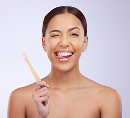 Image showing Portrait, wink or happy girl brushing teeth with smile for healthy oral or dental hygiene in studio. Face, beauty or Brazilian woman model cleaning mouth with a natural bamboo wooden toothbrush