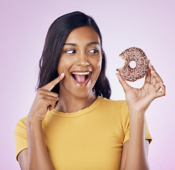 Image showing Donut, dessert and bite with woman in studio for diet, snack and happiness. Sugar, food and smile with female eating sweets treat isolated on pink background for nutrition, excited and craving mockup