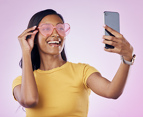 Image showing Sunglasses, selfie smile and Indian woman on pink background with cosmetics, confidence and beauty. Fashion and girl in studio take picture for social media, post and influencer blog