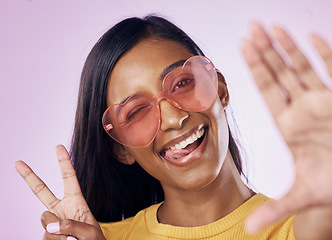 Image showing Selfie, peace and indian woman in studio with heart sunglasses, cheerful or fun on purple background. Portrait, v sign and girl gen z style fashion influencer smile for profile picture or blog post