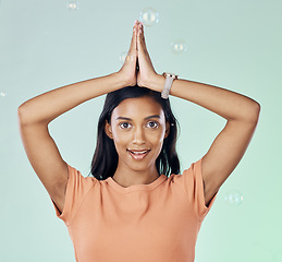 Image showing Portrait, yoga and bubbles with a woman meditating in studio on a gray background for zen or namaste. Fitness, health and wellness with an attractive young female yogi practicing meditation for peace