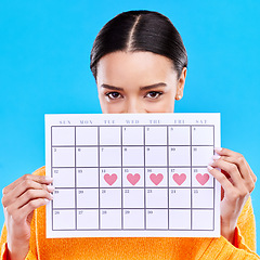 Image showing Calendar, heart and woman on blue background for period schedule, planning and menstruation in studio. Time management, strategy and eyes of girl with month poster for date, weekly planner and cycle