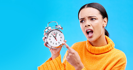 Image showing Frustrated, time and woman with an alarm clock, late and angry against a blue studio background. Female, shouting and person pointing to watch, screaming and schedule with appointment or disagreement